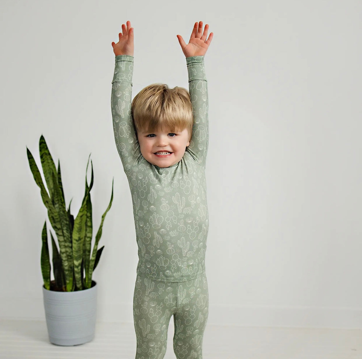 toddler boy wearing sage colored bamboo pajama set with cactus print