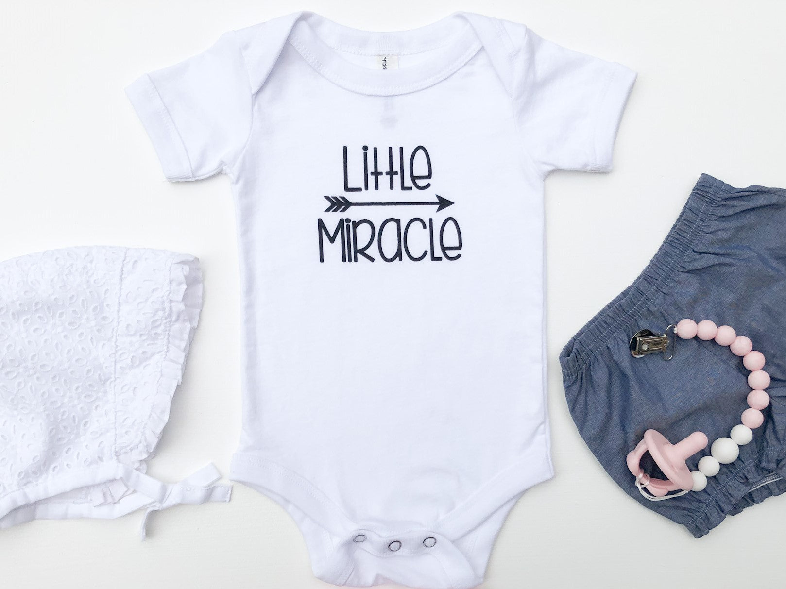 White baby bodysuit with the text Little Miracle