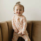baby girl wearing pink baby bamboo pajama romper with daisies and smiley face print