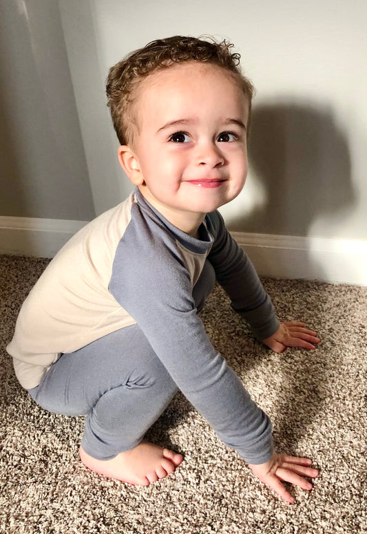 Toddler wearing gray and beige baby pajama set