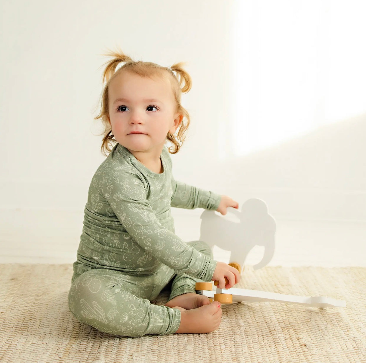 toddler girl wearing sage colored bamboo pajama set with cactus print