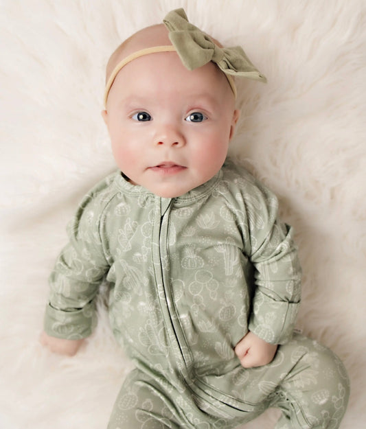 baby girl wearing baby bamboo pajama romper in sage with a cactus print