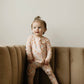 baby girl wearing pink baby bamboo pajama romper with daisies and smiley face print