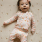 baby girl wearing pink baby bamboo pajama romper with daisies and smiley face print